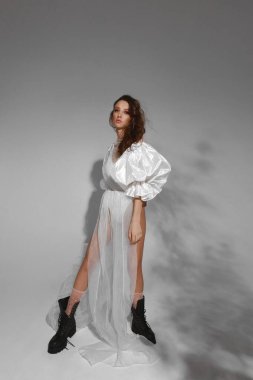 Moda elbisesi içinde bir manken kız ve gri arka planda modaya uygun siyah deri çizmeler. Moda eğilimleri