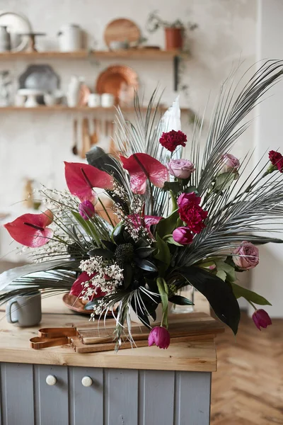 Exotische Blumenkomposition auf dem Holztisch der gemütlichen Küche — Stockfoto