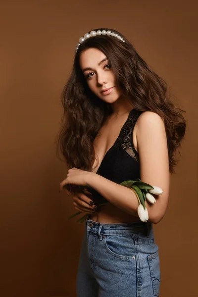 Frühlingsdame mit schönen Tulpenblüten. Porträt einer jungen kaukasischen Model-Frau mit sanftem Make-up posiert mit Tulpenblumen auf beigem Hintergrund lizenzfreie Stockbilder