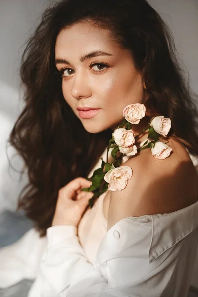 Uma jovem mulher modelo caucasiana com maquiagem suave posando com ramo de flores sobre fundo branco. Menina modelo com ramo de rosas Imagem De Stock
