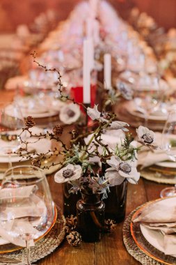 Noel simgeleriyle süslenmiş şenlikli büyük bir masa. Mumlar parıldıyor.