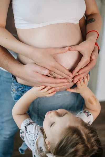 妊娠中の女性と小さな娘は胃に手で心臓を抱え — ストック写真