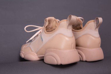 spor ayakkabıları bej renkli, büyük, tek tabanlı gri arka plan.