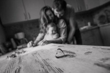 Mutlu bir ailenin arka planına karşı masada kurabiye yapmak için kalp kalıbı.