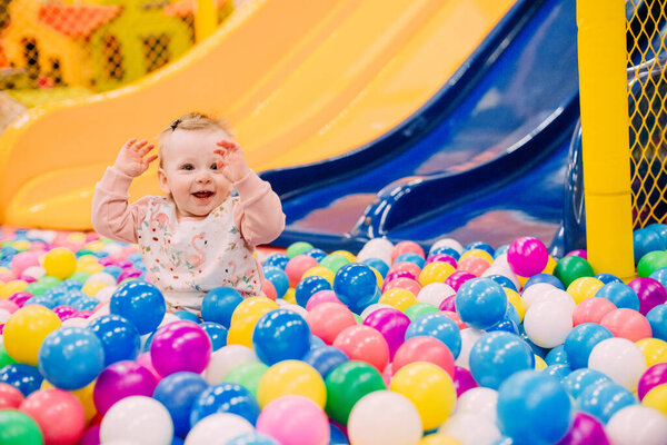 cheerful small child on a playground with a slide and a lot of colorful ball