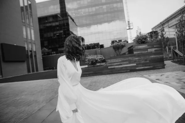 girl bride in a white dress on a large square of a modern cit