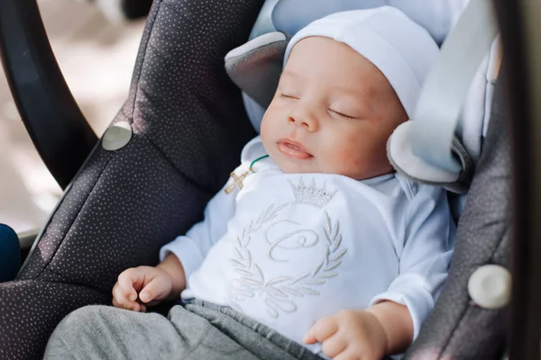 baby sleeping in a car seat with a crown pattern on clothes princes