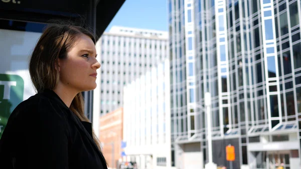 Şehir merkezindeki otobüs durağında otobüs bekleyen kurumsal kadın.