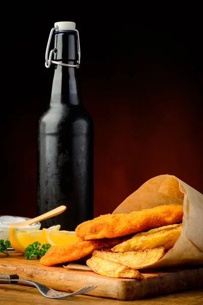 Pesce, patatine fritte e bottiglia di birra — Foto Stock