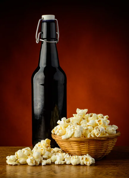 Beer bottle and popcorn snack — Stock Photo, Image