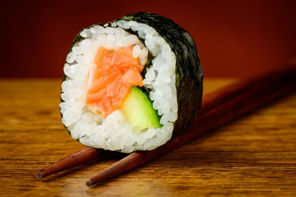 Futomaki sushis roll on chopsticks — Stock Photo, Image