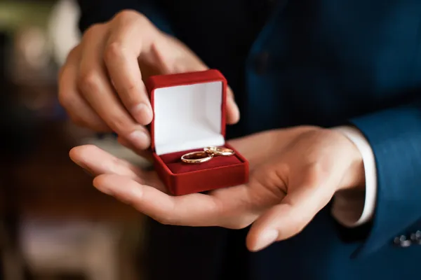 Red gift box with rings in mens hands — Stock Photo, Image