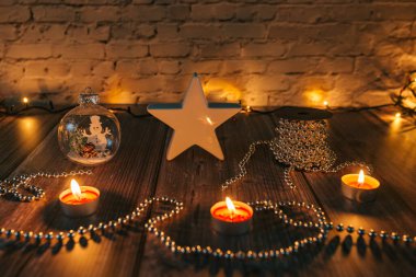 Karanlıktaki yıldız, Noel mumları ve sarı arka plandaki süslemeler.