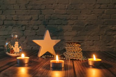 Karanlıktaki yıldız, Noel mumları ve sarı arka plandaki süslemeler.