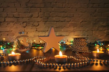 Karanlıktaki yıldız, Noel mumları ve sarı arka plandaki süslemeler.