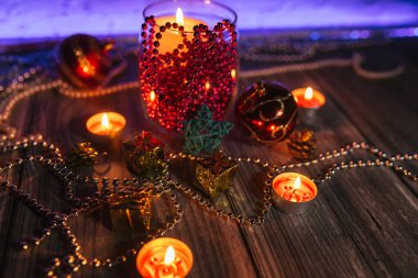 Hediye kutuları, mum ışıkları, kırmızı ve altın rengi Noel süslemeleri mavi arka planda.