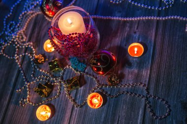 Hediye kutuları, mum ışıkları, kırmızı ve altın rengi Noel süslemeleri mavi arka planda.