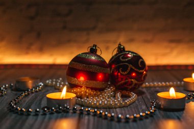 Noel kırmızı topları, mum ışığında dekorasyon, sarı arka plan.