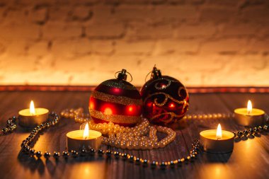 Noel kırmızı topları, mum ışığında dekorasyon, sarı arka plan.