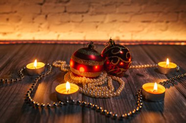 Noel kırmızı topları, mum ışığında dekorasyon, sarı arka plan.