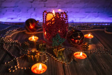 Hediye kutuları, mum ışıkları, kırmızı ve altın rengi Noel süslemeleri mavi arka planda.