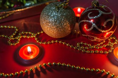 Noel kırmızı ve altın topları, mum ışığında dekorasyon, kırmızı arka plan
