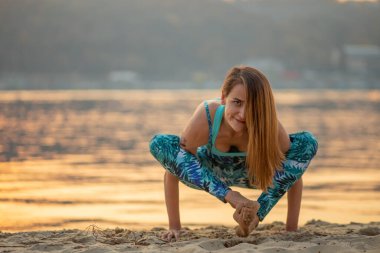 Güzel bir yoga kadını karavanın yanındaki gün batımı kumsalında egzersiz yapar.