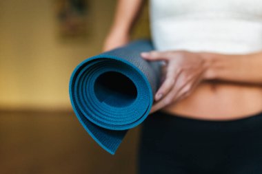  Mavi yoga minderini elinde tutan bir kızın yakın çekimi..