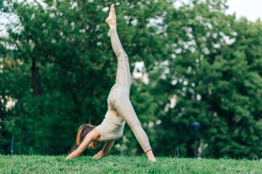 Güzel kız gün batımında yoga yapıyor. Parkta denge, spor, esneme ve rahatlama.