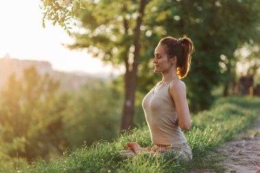 Lotus pozu, güzel bir kız parkta gün batımında meditasyon yapıyor yoga, denge, spor, esneme ve rahatlama.