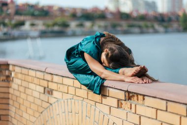 Yeşil elbiseli güzel kız sonbahar parkında yoga yapıyor. Denge, spor, esneme ve rahatlama.