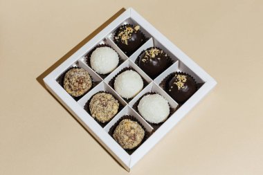 Sarı arka plandaki hediye kutusunda çeşitli el yapımı vejetaryen çikolata şekerlemeleri var.