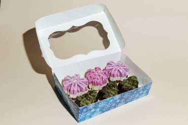 Sarı arka plandaki hediye kutusunda çeşitli el yapımı vejetaryen çikolatalı kekler var.