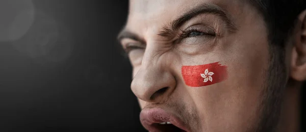 Un homme hurlant avec l'image du drapeau national de Hong Kong sur son visage — Photo