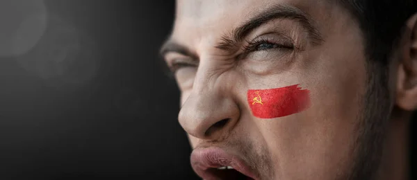 Un homme hurlant avec l'image du drapeau national de l'URSS sur son visage — Photo