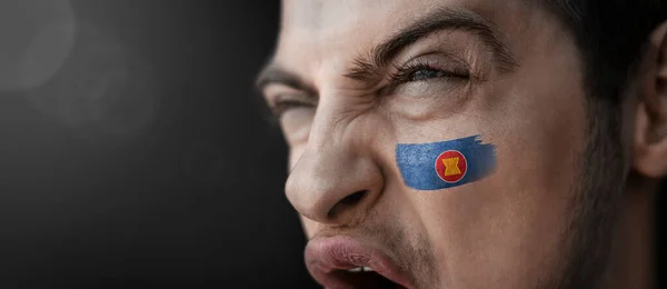 Krzyczący mężczyzna z wizerunkiem flagi narodowej ASEAN na twarzy — Zdjęcie stockowe