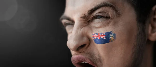 Un hombre gritando con la imagen de la bandera nacional de las Islas Malvinas en su rostro — Foto de Stock