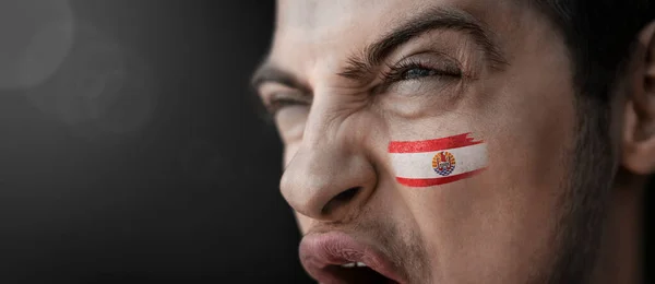 Ein schreiender Mann mit dem Bild der Nationalflagge Französisch-Polynesiens im Gesicht — Stockfoto