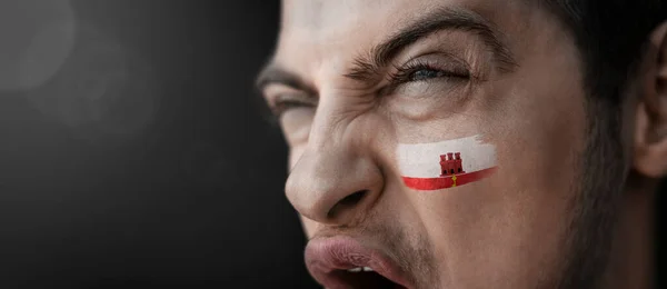 Een schreeuwende man met het beeld van de Gibraltar nationale vlag op zijn gezicht — Stockfoto