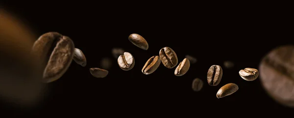 Кофейные зерна в полете на темном фоне — стоковое фото