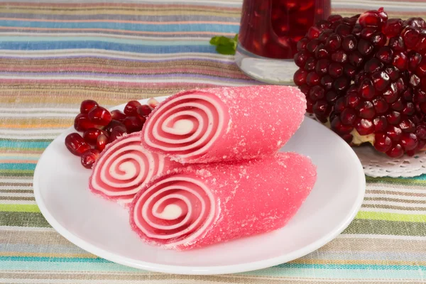 Fruta de doce vermelha em um prato com romã — Fotografia de Stock