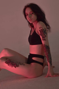 Erotik kız iç çamaşırlarıyla yerde ve pembeyle oturuyor.