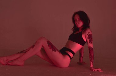 Erotik kız iç çamaşırlarıyla yerde ve pembeyle oturuyor.