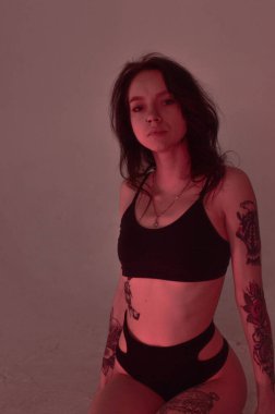 Erotik kız iç çamaşırlarıyla yerde ve pembeyle oturuyor.