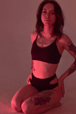 Erotik kız iç çamaşırlarıyla yerde ve pembeyle oturuyor.