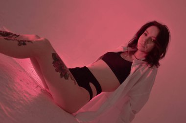 Erotik kız iç çamaşırlarıyla yerde ve pembeyle oturuyor.