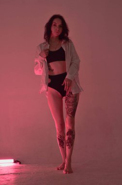 İç çamaşırlı erotik kız pembe neon ışıkta duruyor.