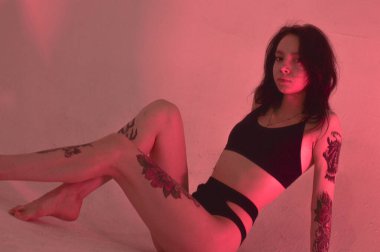 Erotik kız iç çamaşırlarıyla yerde ve pembeyle oturuyor.