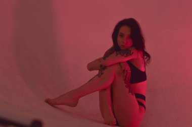 Erotik kız iç çamaşırlarıyla yerde ve pembeyle oturuyor.