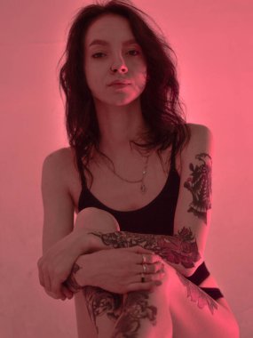 Erotik kız iç çamaşırlarıyla yerde ve pembeyle oturuyor.